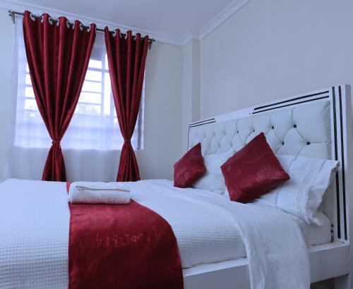 a bedroom with a white bed with red pillows at Lola Homes Thika in Thika