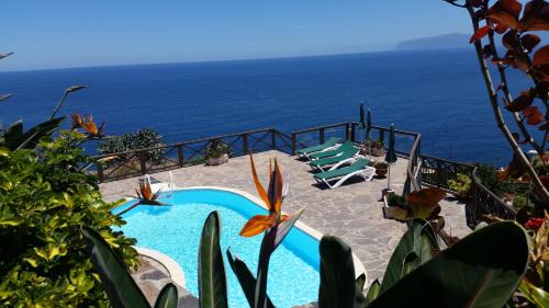 a swimming pool with chairs and the ocean in the background at Viviendas Vacacionales Jardín La Punta in Hermigua