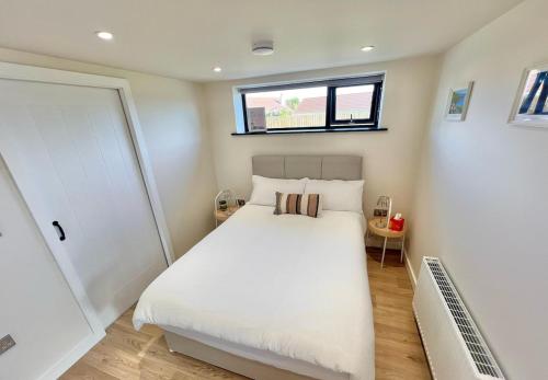 a bedroom with a white bed and a window at Ballyaghran Stay in Portstewart