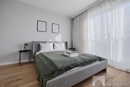 a bedroom with a bed and a large window at Fuzja II by LookAp in Łódź