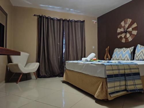 a bedroom with a bed and a chair and a window at Pousada Aruana in Canoa Quebrada