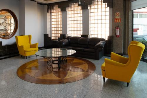 a living room with a coffee table and yellow chairs at Hotel Escala Siglo XXI in Mexico City