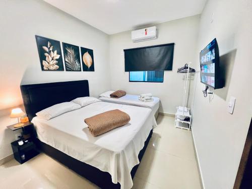a bedroom with a bed and a flat screen tv at Residencial Mª Do Bonfim - 5km Aeroporto JK in Brasília