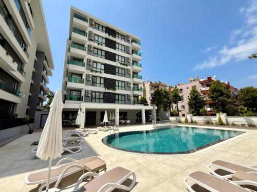 a swimming pool with chairs and umbrellas next to a building at SA Apartments! 150m to the Cleopatra Beach in Alanya