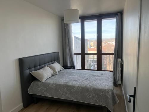 a bedroom with a bed and a large window at Appartement spacieux in Argenteuil
