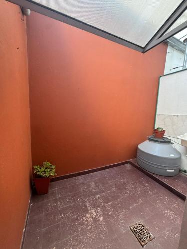 a bathroom with a toilet in an orange wall at Departamento luminoso con balcón in La Plata