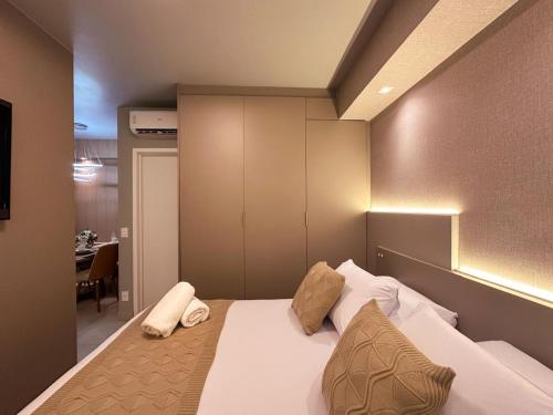 a bedroom with a white bed with pillows on it at Studio Prime Ribeirão Apogeo in Ribeirão Preto
