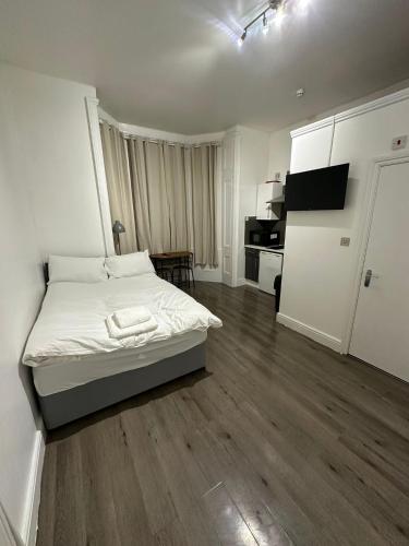 a white bedroom with a bed and a kitchen at Spacious Flat White City in London