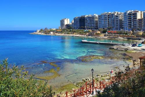 a view of a beach with a boat in the water at Seafront Apartment Sliema in Sliema