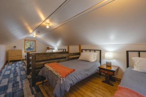 a bedroom with two beds and a table with a lamp at Camp Hudson Pines in Corinth