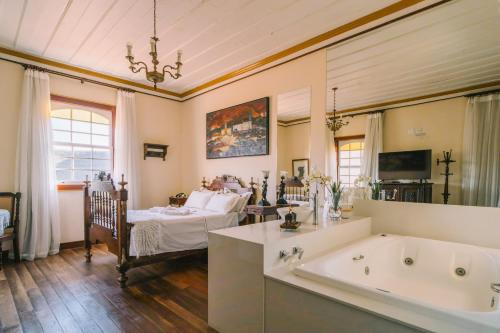 a large bathroom with a tub and a bed at Teatro Hotel Boutique in Ouro Preto