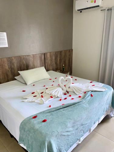 a bed with red rose petals on it at Hotel e Restaurante Star New in Carmópolis