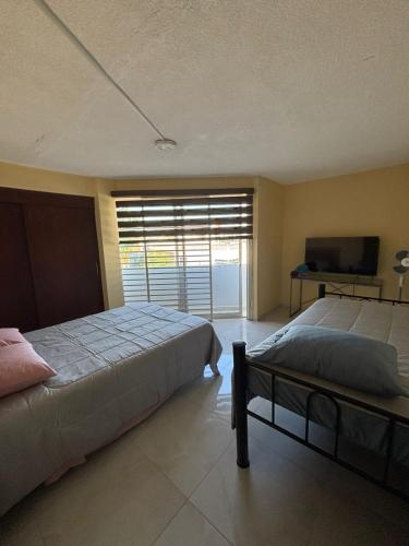 a bedroom with two beds and a flat screen tv at Depa Balbuena in Guadalajara