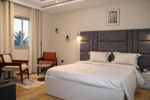 a bedroom with a large white bed and a desk at Empire Luxury Hotel in Yaoundé