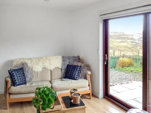 a living room with a couch and a sliding glass door at At Last in Rhiconich