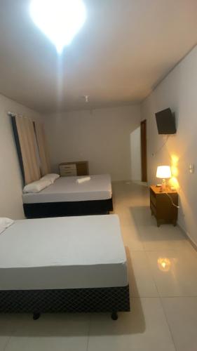 a hotel room with two beds and a tv at Suítes Goiabal in Pirenópolis