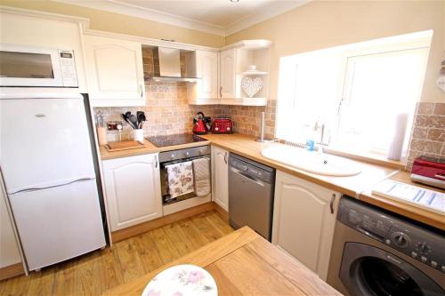 a kitchen with a white refrigerator and a sink at 1 Bed in Gower oc-hh80 in Oxwich