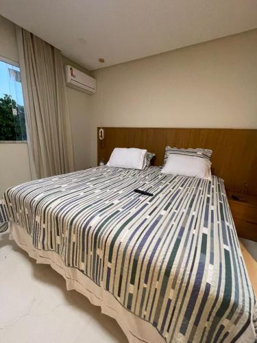 a bedroom with a large bed with a striped comforter at Casa Itacimirim in Camacari