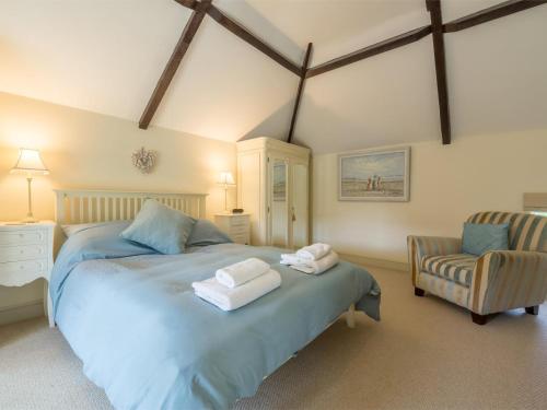 a bedroom with a large bed and a chair at 2 Bed in Dersingham oc-kt082 in Dersingham