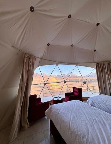 a bedroom with a large bed and a large window at Rina Luxury Camp in Wadi Rum