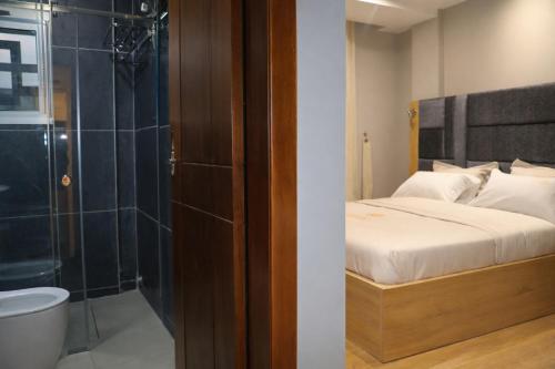 a bedroom with a bed and a shower and a toilet at Empire Luxury Hotel in Yaoundé