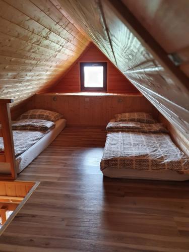 two beds in a attic bedroom with a window at Domki PIĘKNY WIDOK górne - Solina Centrum in Solina