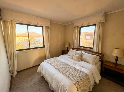 a bedroom with a large bed with two windows at Departamento La Serena Vista al Mar in La Serena