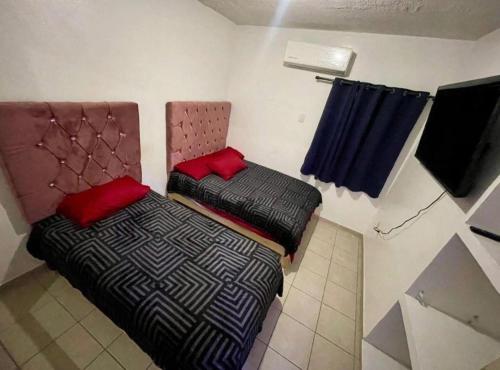 two beds with red pillows in a small room at casa renta vacacional en mazatlan in Mazatlán