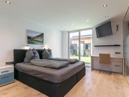 a bedroom with a bed and a desk and a television at Alpin Chalet ARTE in Söll