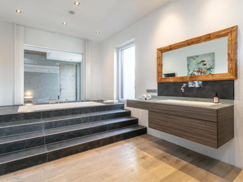 a bathroom with stairs and a tub and a mirror at Alpin Chalet ARTE in Söll