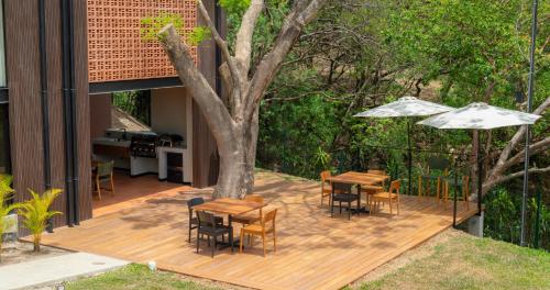 a wooden deck with tables and chairs and an umbrella at BEE Suites Santa Ana - San Jose in San José