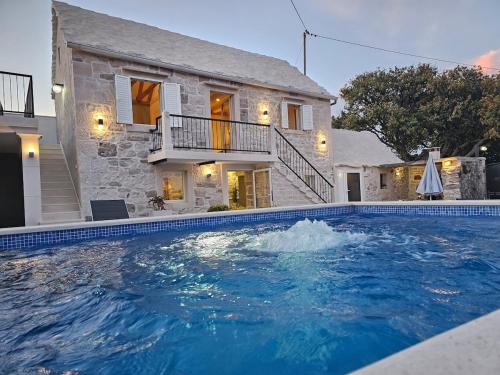 a large swimming pool in front of a house at Authentic Dalmatian stone villa in Selca