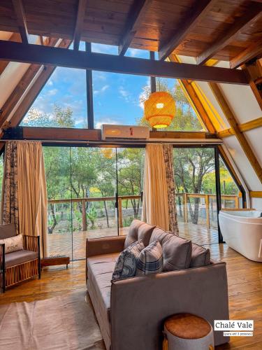 a living room with a couch and a large window at Chalés Exclusivos com Jacuzzi em Bonito Mato Grosso do Sul in Bonito