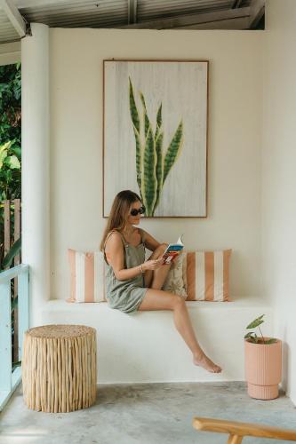 a woman sitting on a couch reading a book at Indie Beach Koh Chang in Ko Chang