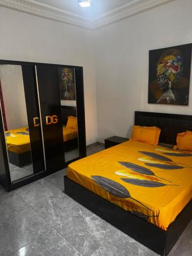 a bedroom with a bed with yellow sheets and a mirror at Kantora Red almadie in Dakar