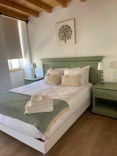 a bedroom with a large white bed with green accents at Casa das Andorinhas - AL in Castelo de Vide