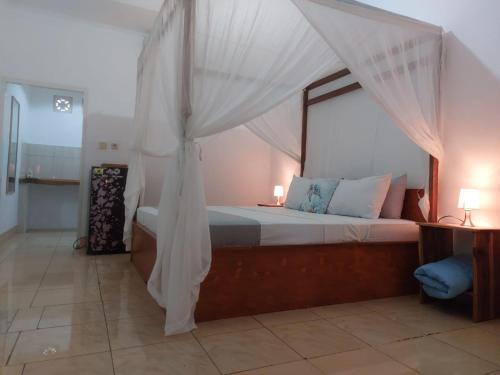 a bedroom with a canopy bed with two lamps at Tapada in Gili Islands