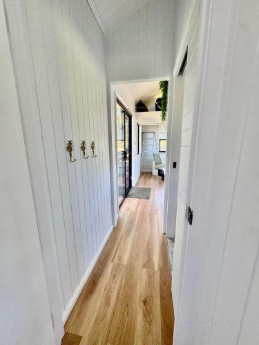 a hallway of a home with white walls and wood floors at El Rancho Cabarita Beach - Highlander in Clothiers Creek
