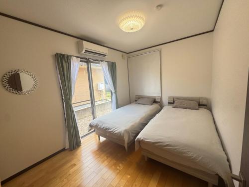 two beds in a room with a window at SerenityBlueAmami in Tatsugo