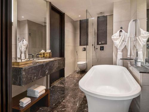 a bathroom with a tub and a sink and a toilet at Pullman New Delhi Aerocity in New Delhi