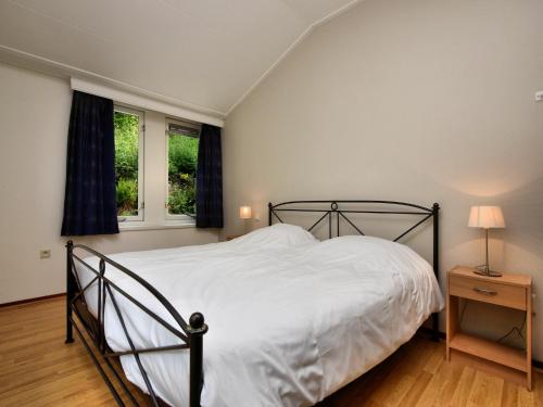 a bedroom with a bed and two windows at Chalet in Odeigne with Private Pool & Sauna in Manhay