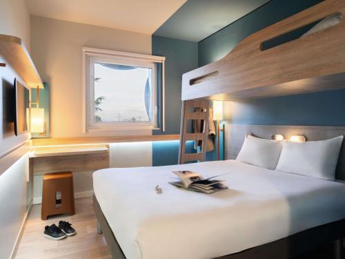 a bedroom with a large white bed with a window at ibis budget Geneve Palexpo Aeroport in Geneva