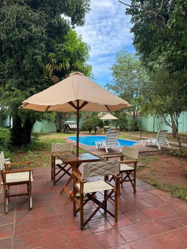 Ein Tisch und Stühle mit einem Sonnenschirm neben einem Pool in der Unterkunft Casa quinta en Capiatá in Capiatá