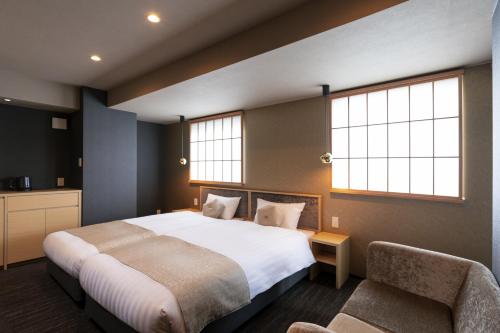 a bedroom with a large bed and two windows at Rinn Horikawa Gojo in Kyoto