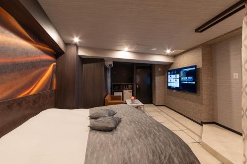 a bedroom with a large bed and a flat screen tv at HOTEL ARIA-Yokohama Kannai in Yokohama