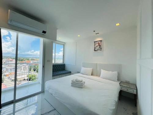 a white bedroom with a white bed and a large window at The Empire Tower by K in Jomtien Beach
