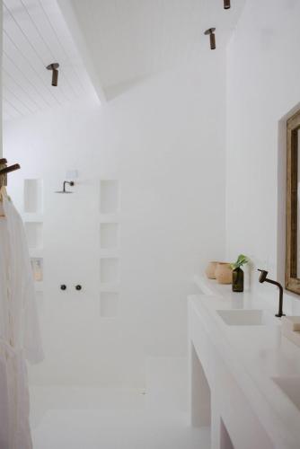 a white bathroom with two sinks and a shower at Vila Figo in Trancoso