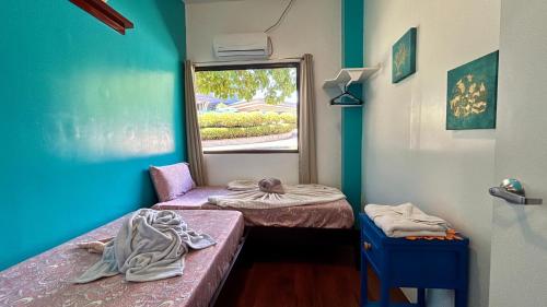 two beds in a room with a window at Ngermid Oasis - Vibrant 2 BD/1 BA Duplex in Ngermid
