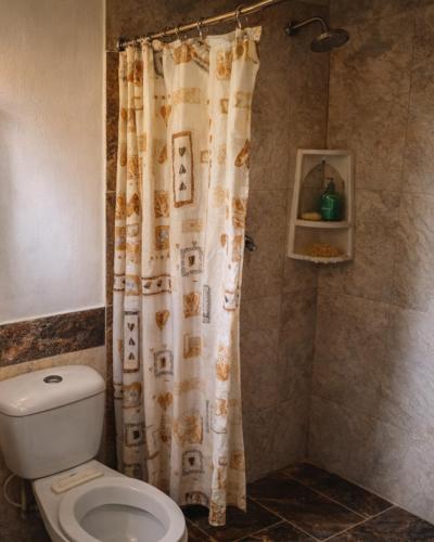a bathroom with a toilet and a shower curtain at Playa Terküa hotel in Nuquí