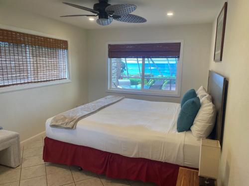 a bedroom with a bed with a ceiling fan and a window at Maui Beach House B & B in Kahana
